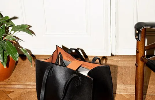 A black bag sitting on the floor next to a chair.