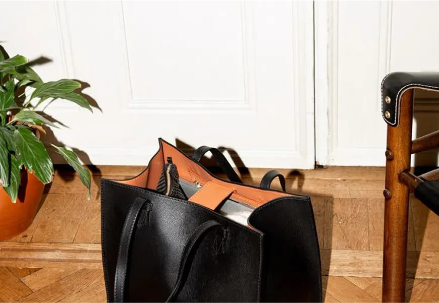 A black bag sitting on top of a wooden floor.